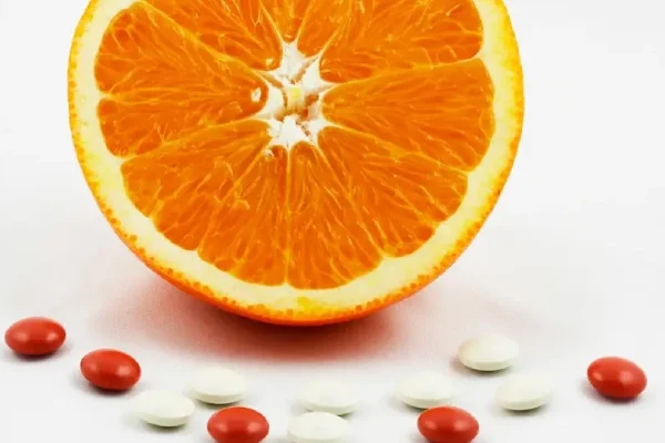 AdobeStock_20436586 (1) Half an orange, surrounded by vitamin and mineral supplement tablets.