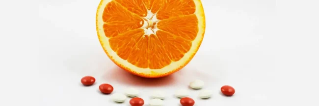 AdobeStock_20436586 (1) Half an orange, surrounded by vitamin and mineral supplement tablets.
