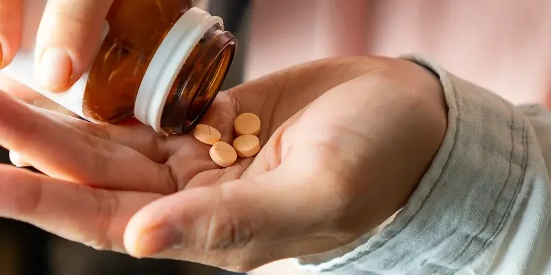 AdobeStock_893541409 Close-up of a woman shaking several supplement tablets out of a bottle into her hand.