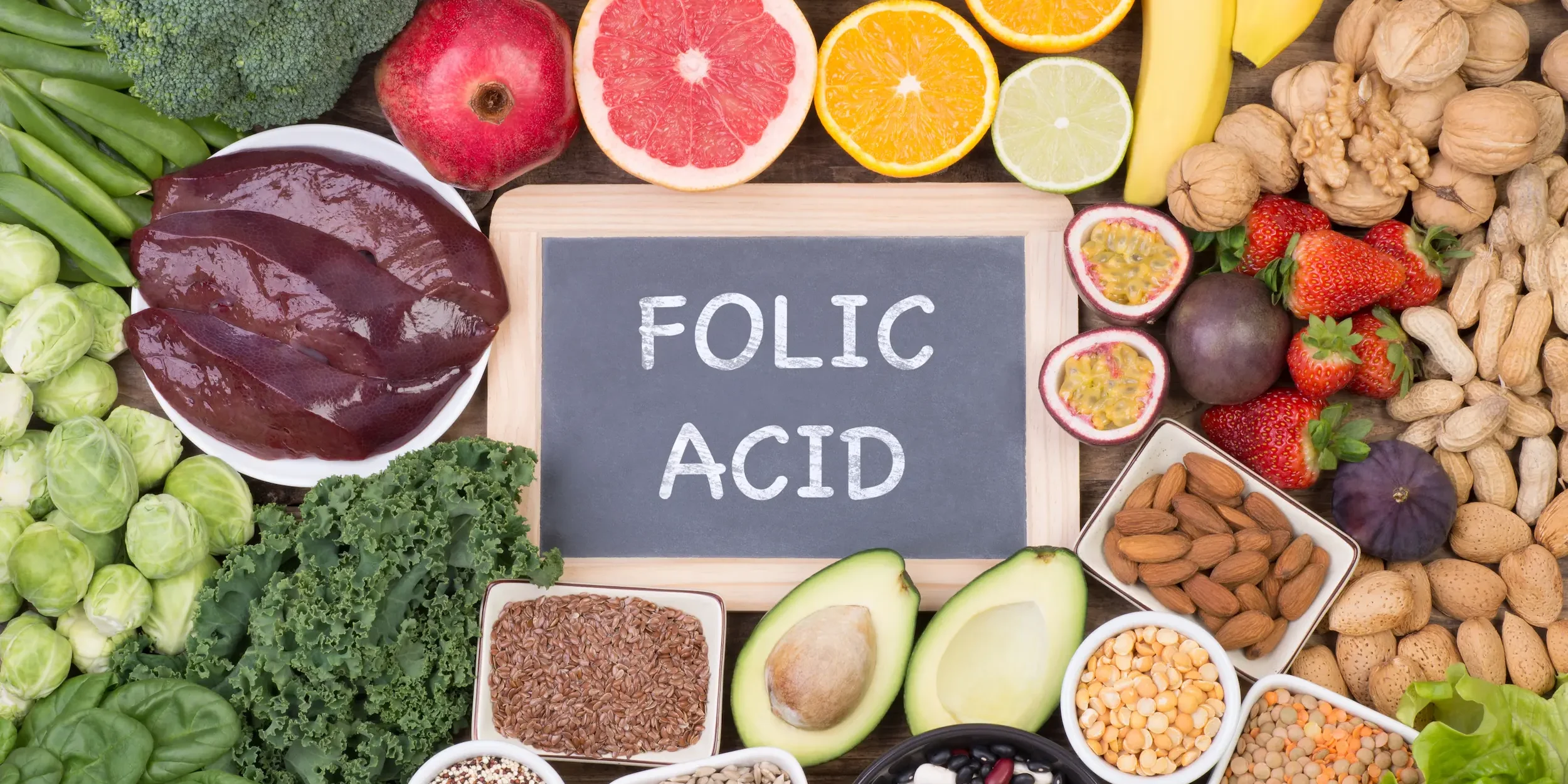 Examples of various healthy foods, including many that are rich in folate, surrounding a chalkboard reading ‘folic acid’.