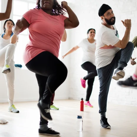 An exercise class engages in aerobic exercise indoors.