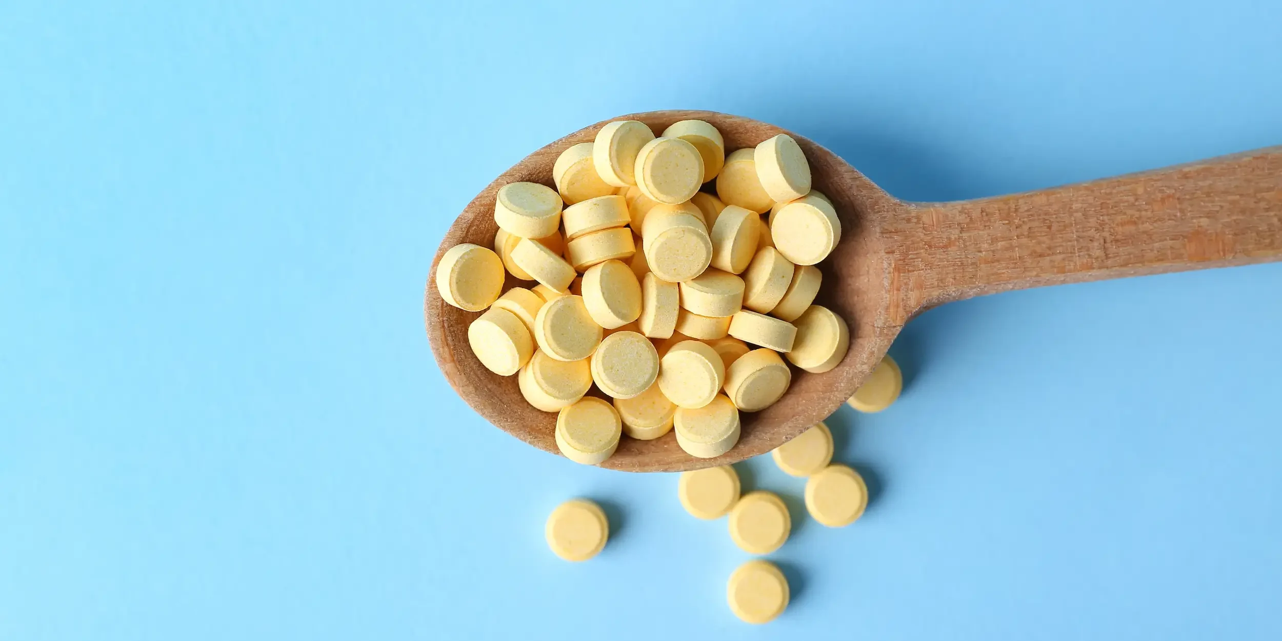 Can You Take Too Much Folic Acid A wooden spoon holding dozens of folic acid tablets, an excessive dose.