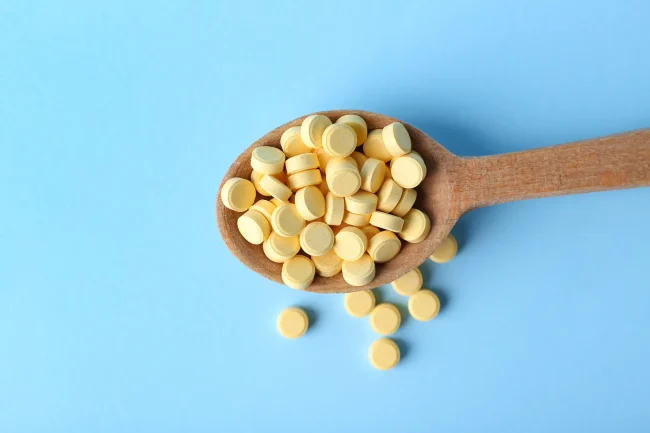 A wooden spoon holding dozens of folic acid tablets, an excessive dose.