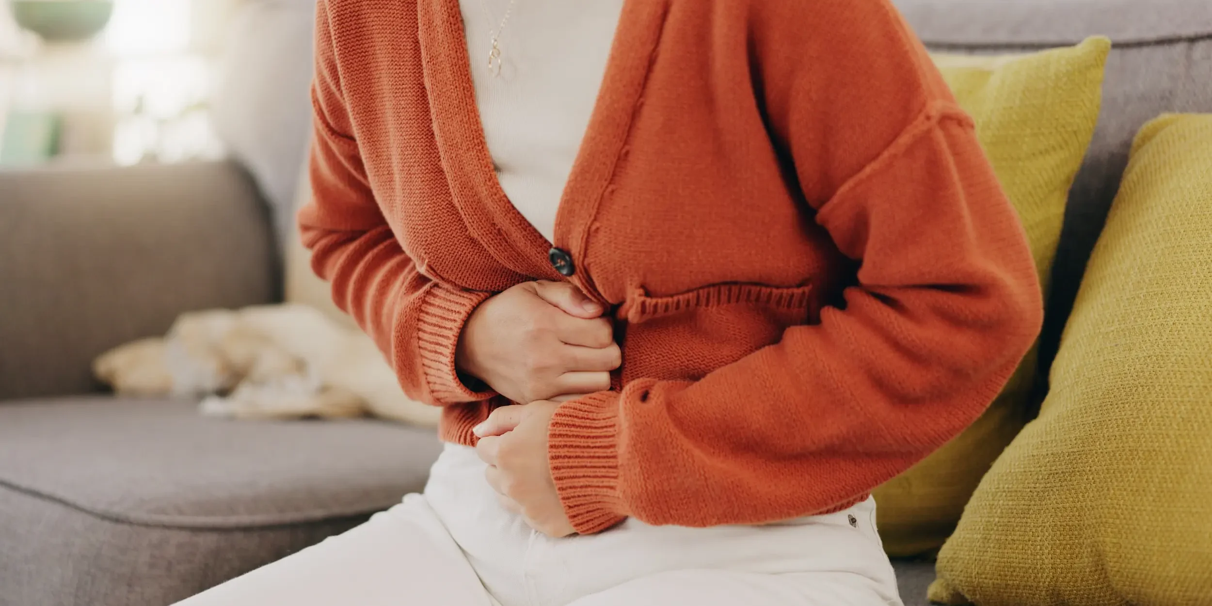 A woman holds her abdomen in pain from a stomach ache, a possible side effect of vitamin B1.