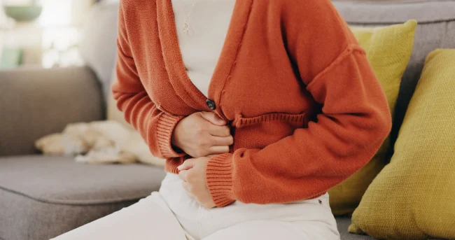 A woman holds her abdomen in pain from a stomach ache, a possible side effect of vitamin B1.