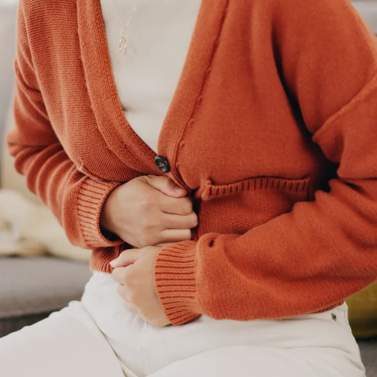 A woman holds her abdomen in pain from a stomach ache, a possible side effect of vitamin B1.