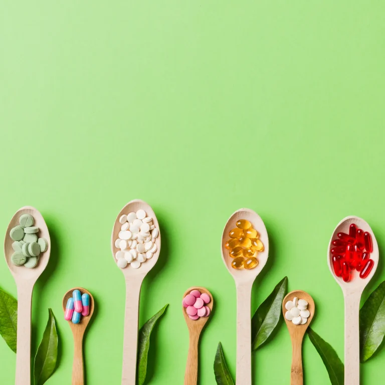 A variety of wooden spoons on a green background, each holding different mineral supplements.