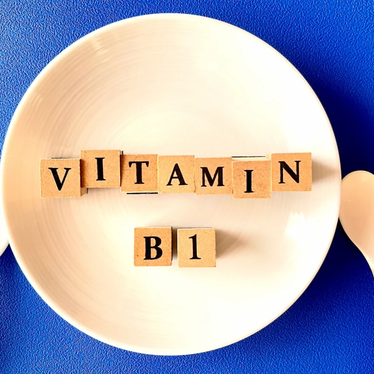 The words ‘Vitamin B1’ spelled on wooden cubes on a dinner plate with cutlery beside it.
