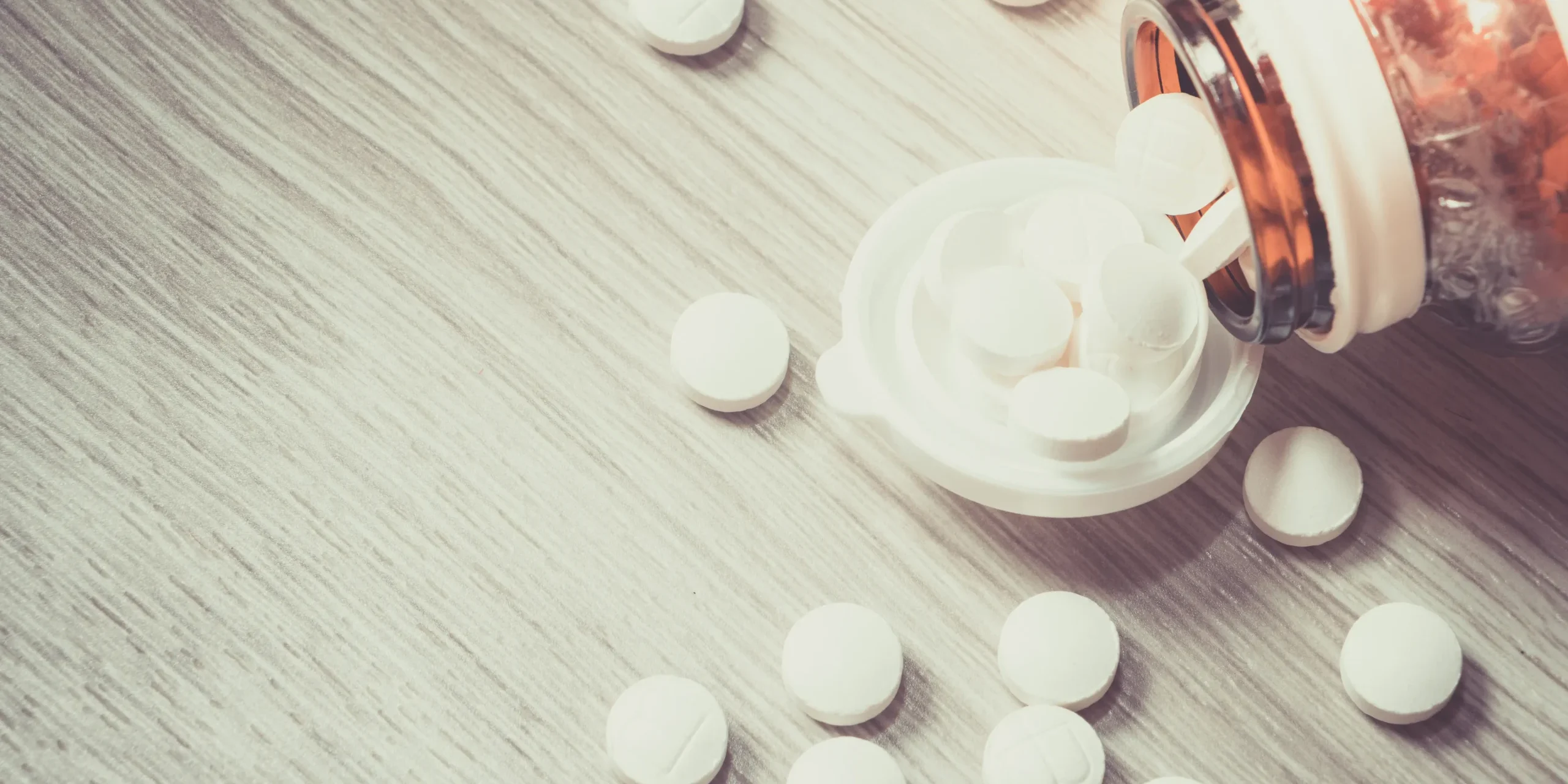 Can you overdose on zinc supplements Pills spill out of a bottle onto a wooden table, representing an excessive dose.