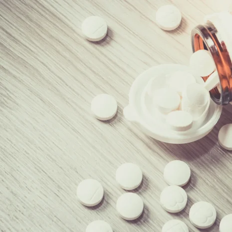 Can you overdose on zinc supplements Pills spill out of a bottle onto a wooden table, representing an excessive dose.