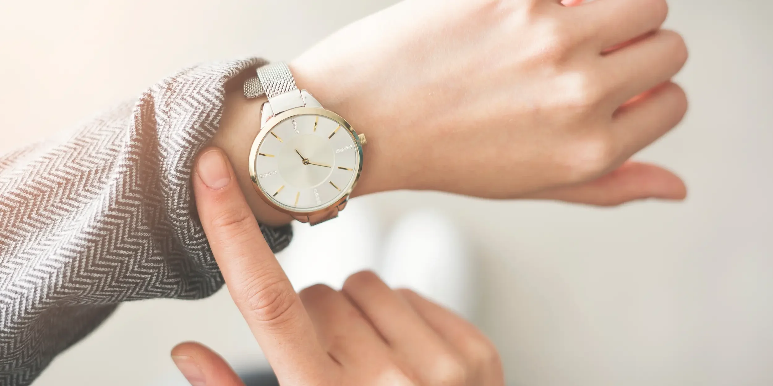 A woman checks the time on her wristwatch, representing waiting to see results.