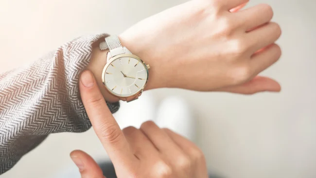 A woman checks the time on her wristwatch, representing waiting to see results.