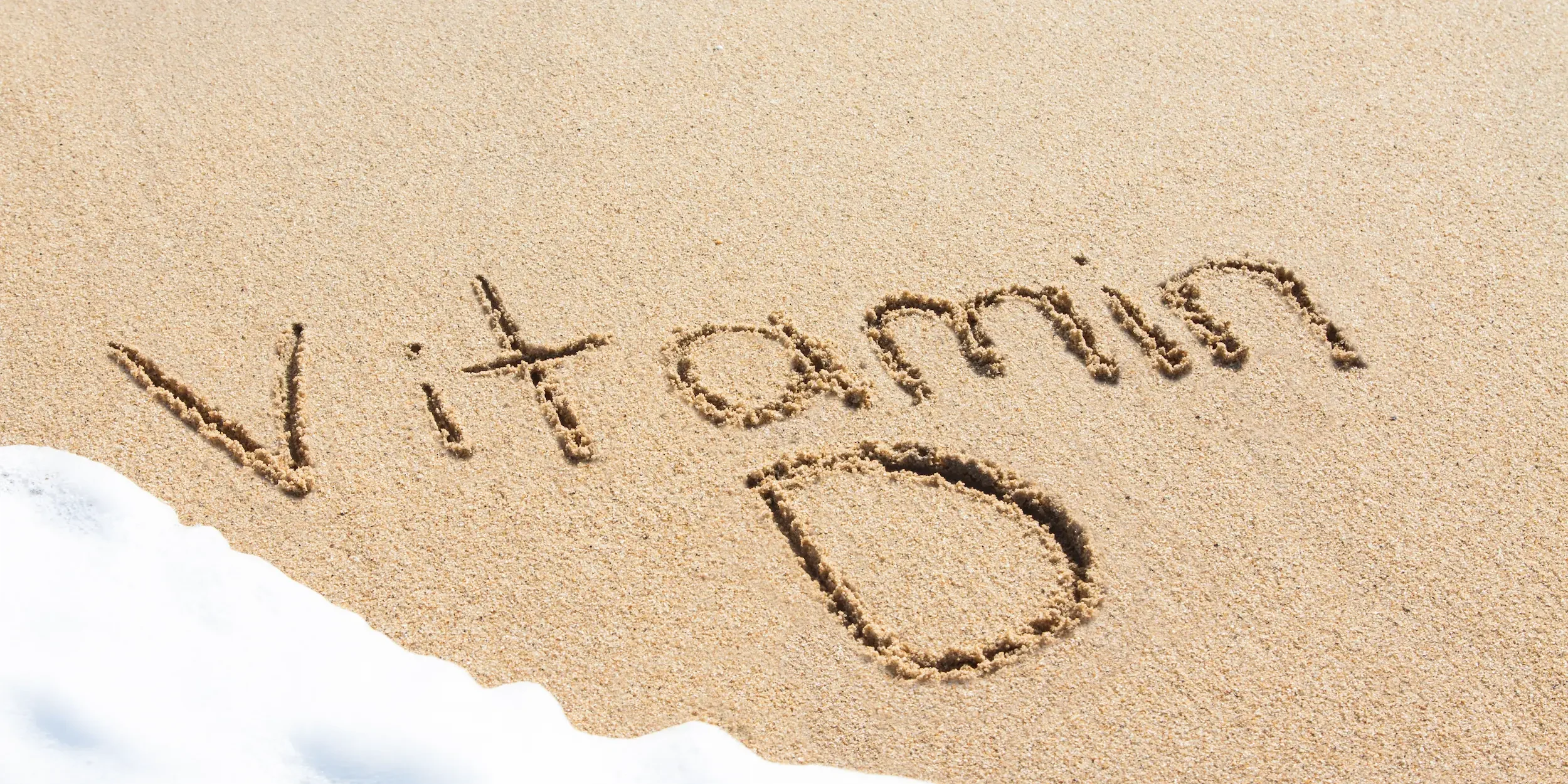 What helps vitamin D absorption The words ‘Vitamin D’ written in the sand, with waves about to wash it away