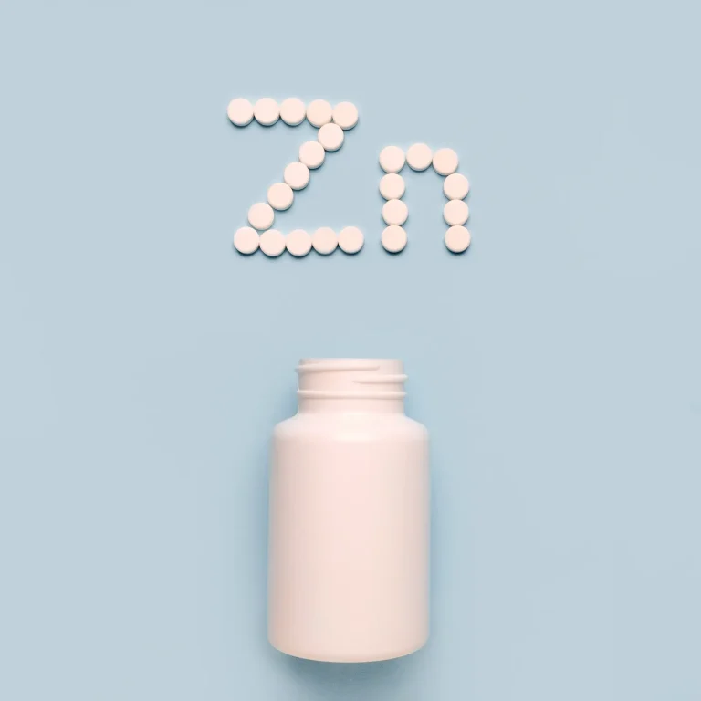 When to take zinc supplements Small white pills spell out ‘Zn’ for zinc above a white pill bottle on a pale blue background.