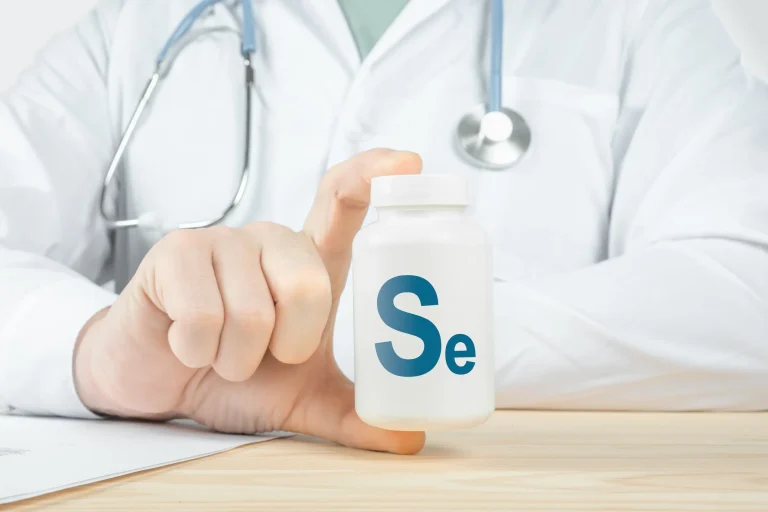 Close-up of a doctor holding a white pill bottle labelled ‘Se’ for selenium.