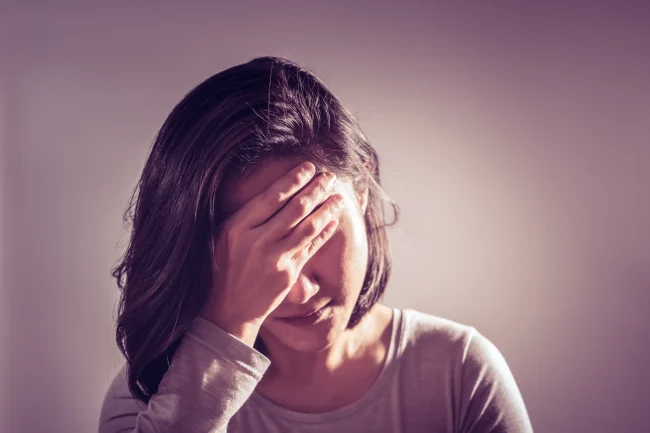 A young woman holds her forehead in her hand, feeling a headache from dehydration. A young woman holds her forehead in her hand, feeling a headache from dehydration.